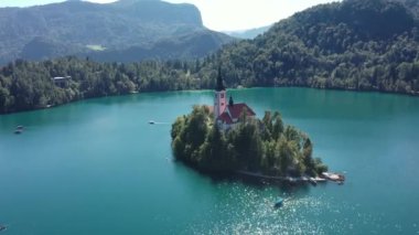 Gölün ortasındaki Mary Varsayımı Kilisesi Bled. Slovenya. Havadan. Yaz. İnsansız hava aracı videosu. Bled Gölü 'nde küçük bir adada uçmak. Mavi su ve orman..