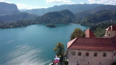 Slovenya 'daki Aerial of Bled Castle veya Blejski mezunu, ön planda Bled Gölü ve Karawanks Dağları ile birlikte. Yaz. İnsansız hava aracı videosu. Günaydın.