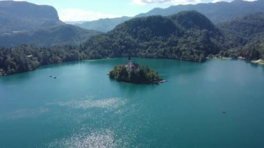 Gölün ortasındaki Mary Varsayımı Kilisesi Bled. Slovenya. Havadan. Yaz. İnsansız hava aracı videosu. Bled Gölü 'nde küçük bir adada uçmak. Mavi su ve orman..
