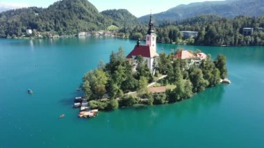 Gölün ortasındaki Mary Varsayımı Kilisesi Bled. Slovenya. Havadan. Yaz. İnsansız hava aracı videosu. Bled Gölü 'nde küçük bir adada uçmak. Mavi su ve orman..