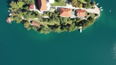 Gölün ortasındaki Mary Varsayımı Kilisesi Bled. Slovenya. Havadan. Yaz. İnsansız hava aracı videosu. Bled Gölü 'nde küçük bir adada uçmak. Mavi su ve orman..