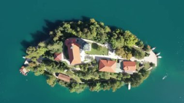 Gölün ortasındaki Mary Varsayımı Kilisesi Bled. Slovenya. Havadan. Yaz. İnsansız hava aracı videosu. Bled Gölü 'nde küçük bir adada uçmak. Mavi su ve orman..
