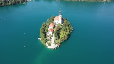 Gölün ortasındaki Mary Varsayımı Kilisesi Bled. Slovenya. Havadan. Yaz. İnsansız hava aracı videosu. Bled Gölü 'nde küçük bir adada uçmak. Mavi su ve orman..