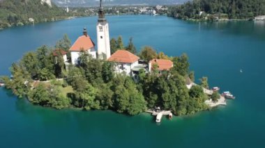 Gölün ortasındaki Mary Varsayımı Kilisesi Bled. Slovenya. Havadan. Yaz. İnsansız hava aracı videosu. Bled Gölü 'nde küçük bir adada uçmak. Mavi su ve orman..