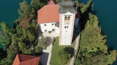 Gölün ortasındaki Mary Varsayımı Kilisesi Bled. Slovenya. Havadan. Yaz. İnsansız hava aracı videosu. Bled Gölü 'nde küçük bir adada uçmak. Mavi su ve orman..