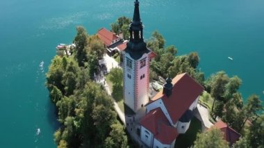 Gölün ortasındaki Mary Varsayımı Kilisesi Bled. Slovenya. Havadan. Yaz. İnsansız hava aracı videosu. Bled Gölü 'nde küçük bir adada uçmak. Mavi su ve orman..