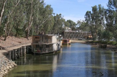 ECHUCA, AUSTRALIA - 1 Mart 2020: Murray Nehri 'ndeki demirlemiş nehir teknelerini geçerek Echuca' daki tarihi kırmızı sakız iskelesine doğru bakıyor