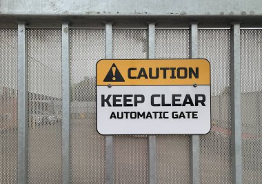 Sarı, siyah ve beyaz dikkat, Metal bir işyeri kapısına vidalanmış Otomatik Kapı Güvenlik Uyarısı 