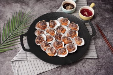 Kore kan midyelerini kaynatıp soya sosu ve gochujang (kırmızı biber ezmesi) soslu siyah bir tabağa yerleştirmek.