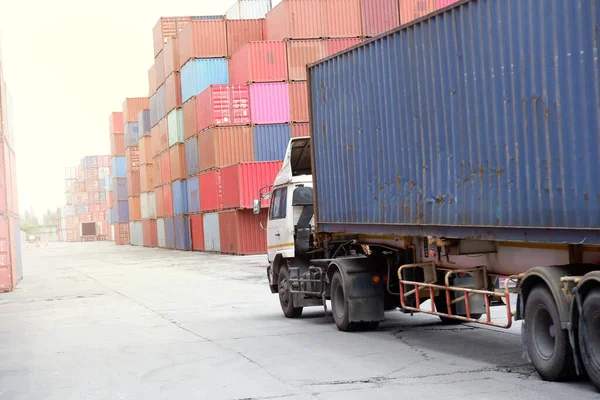 A container truck sits behind a pile of containers.