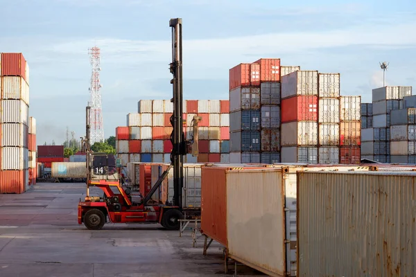 Forklift malları, konteynır kutuları lojistik avlusunda ve arkasında konteynır yığını var.