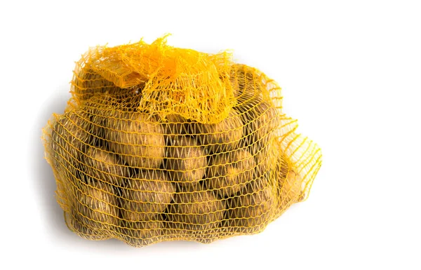 未洗净的土豆在白色背景的网状结构中 免版税图库照片