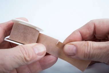 Elinde beyaz bir paten ile tıbbi yapıştırıcıyı yırt.