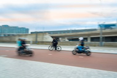 Bulanık bir arkaplanda hareket eden bisikletçi ve motosikletçi