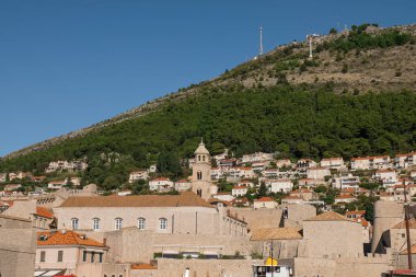 Dubrovnik eski kasaba duvarları üzerinde yeni bir yerleşim alanı ve yeşil kozalaklı ağaçlar var.
