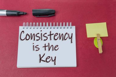 Consistancy kırmızı arkaplandaki defterde yazan anahtar işarettir.