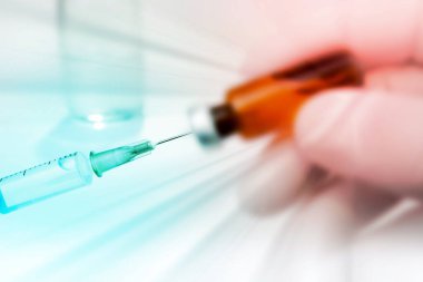 Aşı ve Enjeksiyon. Laboratuvarda çalışan bir bilim adamı, çocuklar ve yetişkinler için sıvı aşılarla dolu bir şırınga tutuyor.