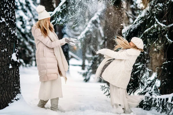 暖かい母親と娘は冬の時間に楽しい屋外を楽しんでいます 雪の木々の間で雪遊び — ストック写真