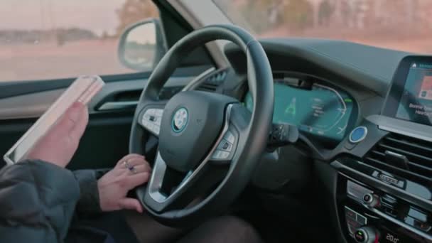 新しい電気自動車のハンドルに女性のビューBmw Ix3は モバイルでサーフィンすることによって気を散らしました スウェーデンだ ウプサラ 2022 — ストック動画
