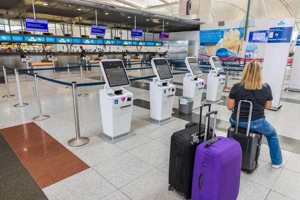 在机场 看到一个女人坐在手提包上 站在行李投递标志前 2022 — 图库照片
