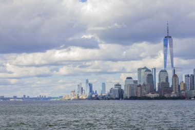Hudson Nehri 'nin her iki yakasındaki Manhattan gökdelenlerinin mavi gökyüzünün altında beyaz bulutlar var. New York, ABD.