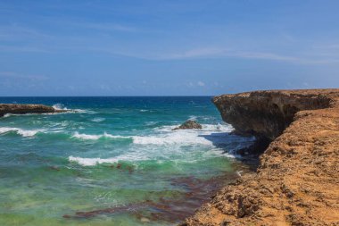 Aruba adasının kayalık kıyı şeridi çok güzel. Turkuaz dalgalar Atlantik okyanusu ve gökyüzü ufukta birleşir. 