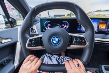 Elektrikli araba BMW IX40 'ın direksiyonundaki kadın ellerini yakından izle. İsveç. Uppsala. 09.25.2022.