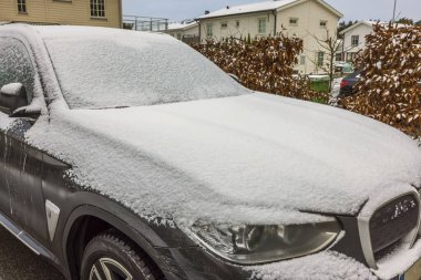 Kış günü özel otoparkta karla kaplı elektrikli arabaları kapatın. İsveç.