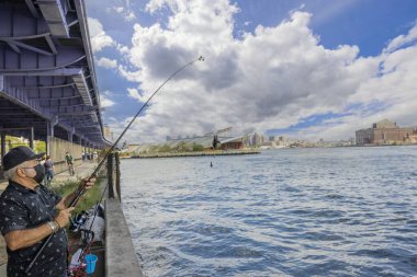 Brooklyn Köprüsü 'nün altında oltayla balık tutan balıkçılara yakın durun. New York, ABD. 09.21.2022.