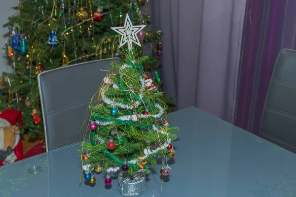 Close up view of small artificial Christmas tree with toys standing on table in room. Sweden.
