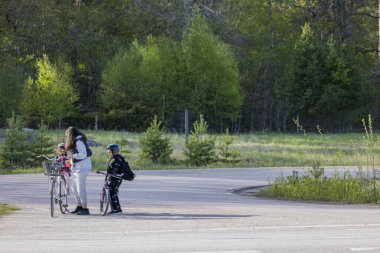 Yeşil alanda bisikletli anne ve iki çocuğunun güzel manzarası. Aktif yaşam tarzı konsepti. İsveç. Uppsala. 05.18.2022.