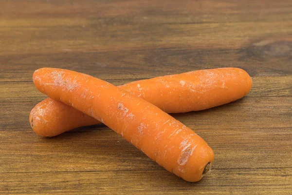 Close up view of two carrots isolated on wooden background.