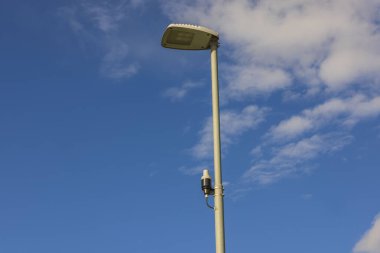 Mavi gökyüzünde, ender bulunan beyaz bulutlarla aydınlatma direğindeki ışık sensörü teknolojisi. İsveç. 