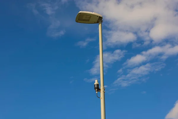 Technology view of light sensor on street lighting pole on blue sky with rare white clouds background. Sweden.