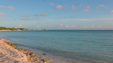 Kumlu sahil şeridi manzarası ve Atlantik Okyanusu 'nun sakin su yüzeyi ufukta mavi gökyüzü ile birleşiyor. Aruba. 