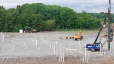 İnşaat alanının inşaatı için beton yığınları toprağa gömülecek. Enkoping. 08.25.2022.