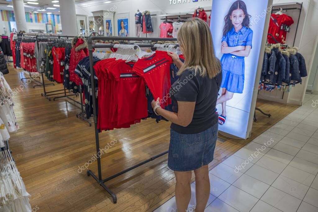 Vista de cerca de la mujer que elige la camiseta para niños Tommy Hilfiger  para niños en la tienda Macy 's. Nueva York. Estados Unidos. 09.21.2022.  2023