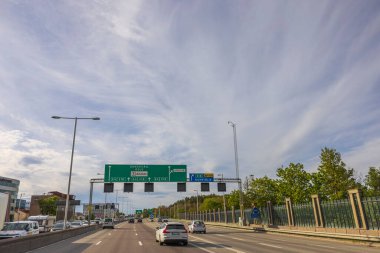 Ufukta bulutlu mavi gökyüzü ile birleşen çok şeritli yol manzarası. Yol şeritlerinin üzerindeki yeşil yol işaretleri. İsveç. Stockholm. Avrupa. 05.18.2022.