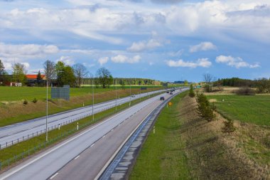 View from bridge to motorway running along fields against blue sky with white clouds. Sweden. Uppsala. 08.25.2022.