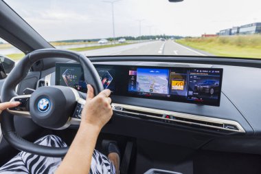 Elektrikli arabanın iç manzarası BMW iX40 yolda. Araçtaki kadın sürücü. İsveç. Uppsala. 08.25.2022.