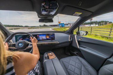 Elektrikli araba BMW iX40 'ın güzel iç manzarası yolda. Araçtaki kadın sürücü. İsveç. Uppsala. 08.25.2022.