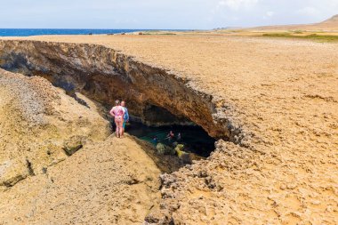 Beautiful view of tourists swimming in natural cave on Atlantic Ocean coastline. Aruba. Oranjestad. 02.12.2023.