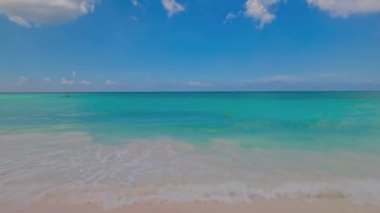 Beautiful view of sandy beach with turquoise water of Atlantic Ocean against blue sky with white clouds. Aruba.