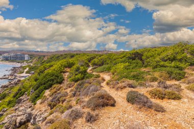 Akdeniz kıyılarında beyaz bulutlu mavi gökyüzünün arka planına karşı duran dağların tepesinden otellere kadar manzarayı izle.