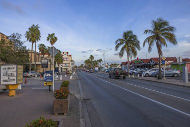 Şehir merkezindeki Oranjestad şehrinde gün batımında geçen arabalarla güzel bir otoyol manzarası. Aruba. Oranjestad. 03.18.2023.