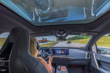 BMW iX 40 'ın güzel iç manzarası yolda. Kadın sürücü otoyolda araba kullanıyor. İsveç. Uppsala. 08.18.2022.