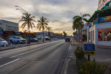 Oranjestad Aruba Adası 'nın merkezinde gün batımında dükkanları olan güzel bir otoyol manzarası. Aruba. Oranjestad. 03.24.2023.