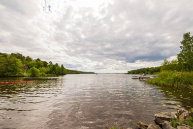 Yeşil orman ağaçlarıyla çevrili muhteşem bir göl manzarası. İsveç. 