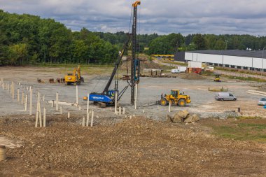 İnşaat alanının inşaatı için beton yığınları toprağa gömülecek. İsveç. Enkoping. 08.25.2022.