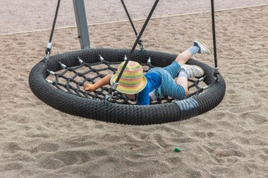 Çocuk parkında salıncakta sallanan çocuğun yakın görüntüsü. İsveç.